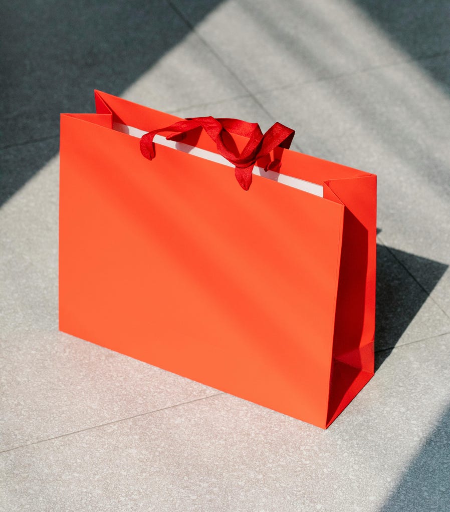 High angle of bright paper present bag with handles placed on tiled floor at sunlight